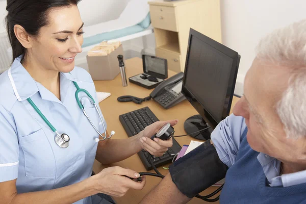 Enfermeira britânica tomando a pressão arterial do homem sênior — Fotografia de Stock