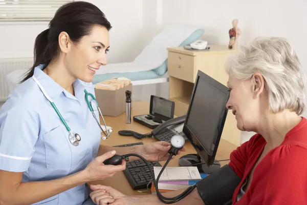 Enfermera británica tomando la presión arterial de la mujer mayor —  Fotos de Stock