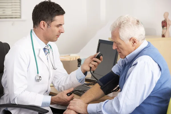 Amerykański lekarz biorąc starszy człowiek ciśnienie krwi — Zdjęcie stockowe