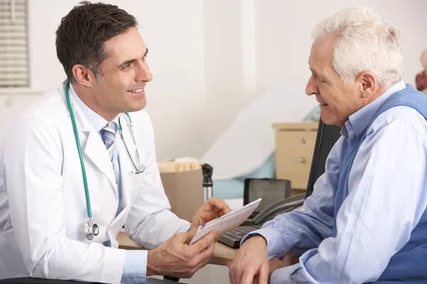 Medico americano che parla con un uomo anziano in chirurgia — Foto Stock