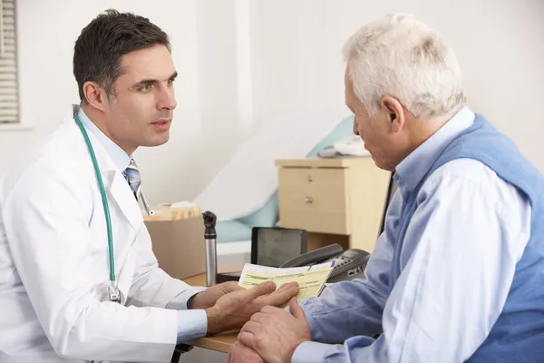 Amerykański lekarz mówi do starszy człowiek w chirurgii — Zdjęcie stockowe