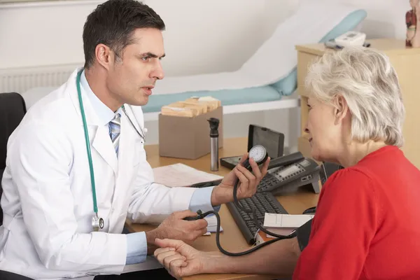 Médico americano tomando la presión arterial de la mujer mayor —  Fotos de Stock