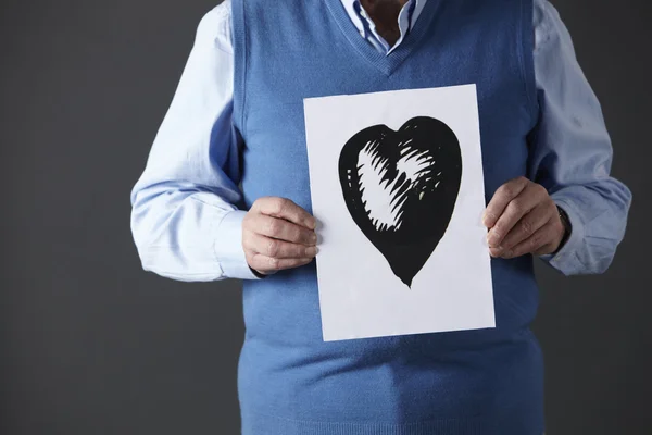 Hombre mayor sosteniendo tinta dibujo de corazón — Foto de Stock