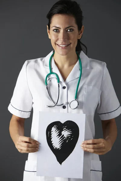 Enfermeira americana segurando tinta desenho do coração — Fotografia de Stock