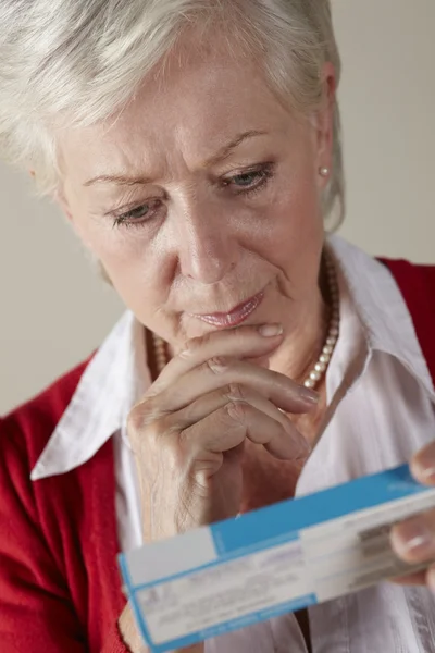 Mulher sênior olhando para o pacote de medicamentos prescritos — Fotografia de Stock