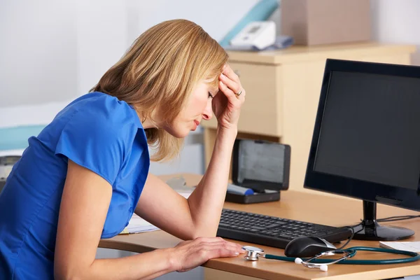 Stressato medico britannico seduto alla scrivania — Foto Stock