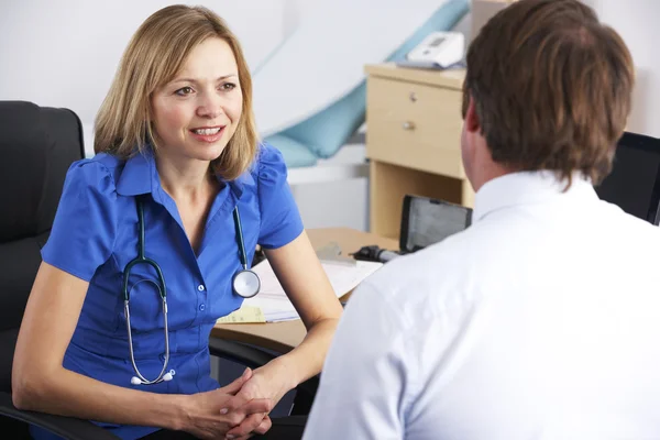 Vrouwelijke Britse arts praten met mannelijke patiënt — Stockfoto