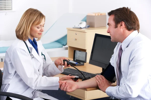 Amerykański lekarz biorąc ciśnienia krwi pacjenta — Zdjęcie stockowe