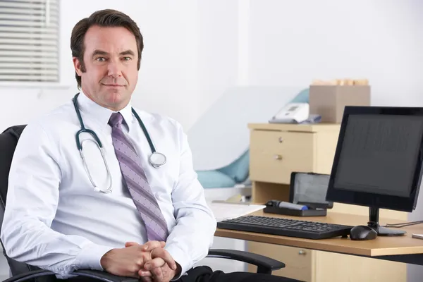 Retrato médico del Reino Unido sentado en el escritorio — Foto de Stock