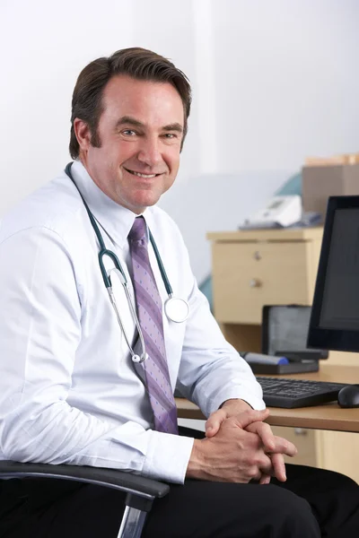 Portrét britské doktor sedí u stolu — Stock fotografie