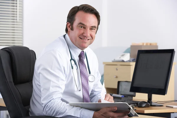 Porträtt brittiska läkare sitter vid skrivbord — Stockfoto