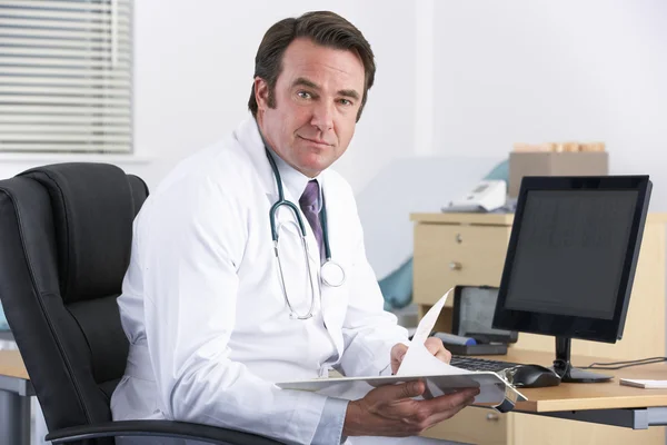 Retrato UK médico sentado na mesa — Fotografia de Stock