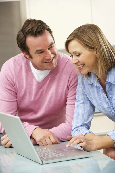 Mature couple using laptop in domestic kitchen — Stock Photo, Image