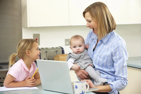 Mutter mit Kindern benutzt Laptop in Küche — Stockfoto