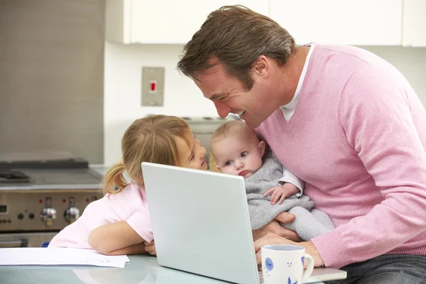 Vader met kinderen met behulp van laptop in de keuken — Stockfoto