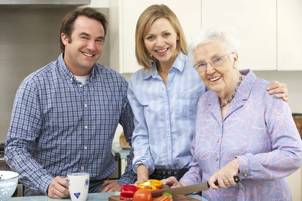 Seniorin und Familie bereiten gemeinsam Mahlzeit zu — Stockfoto
