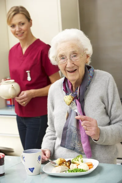 Mulher idosa com cuidador comer refeição em casa — Fotografia de Stock