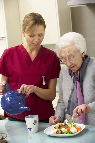 Seniorin mit Pflegerin zu Hause beim Essen — Stockfoto