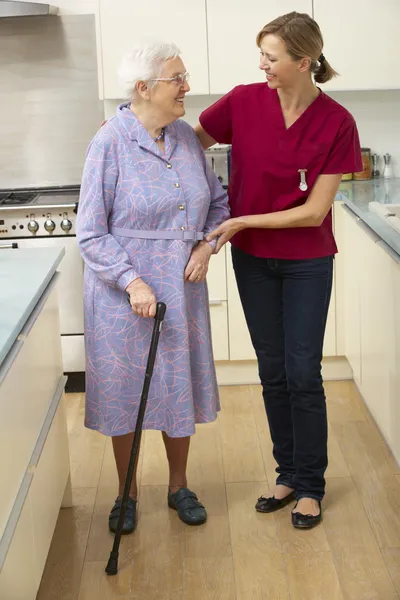 Äldre kvinna och vårdare i köket — Stockfoto