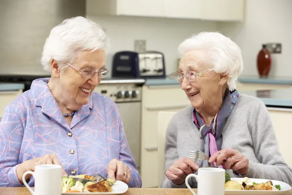 Senior vrouwen genieten van maaltijd thuis samen — Stockfoto