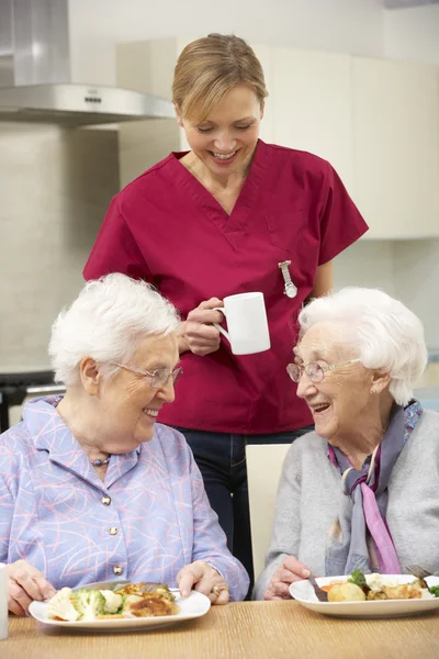 Senior vrouwen met verzorger genieten van maaltijd thuis — Stockfoto