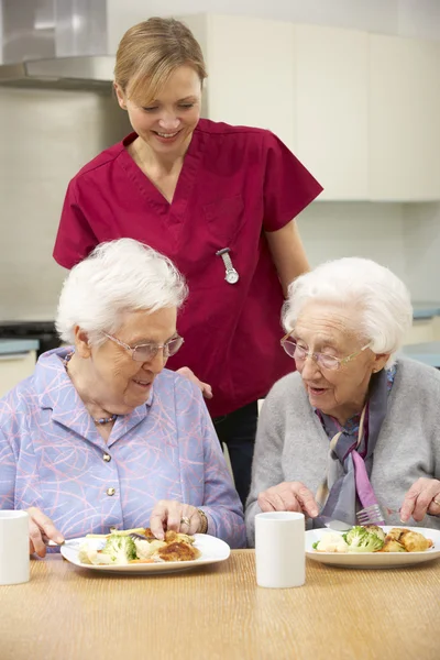 Mujeres mayores con cuidador disfrutando de la comida en casa —  Fotos de Stock