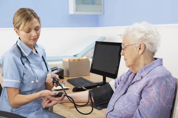 Britse verpleegster nemen senior vrouw bloeddruk — Stockfoto
