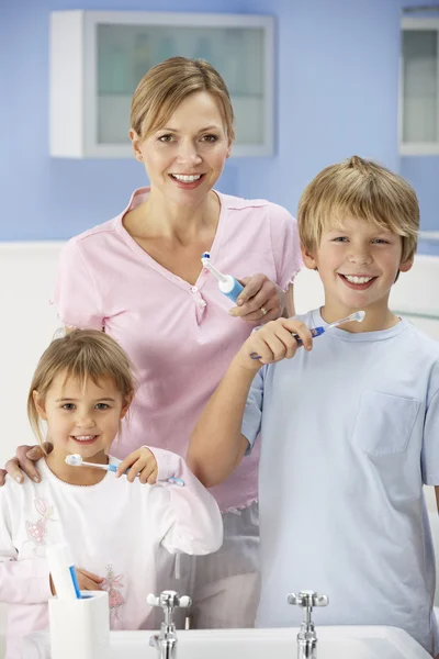 Madre e bambini che puliscono i denti in bagno — Foto Stock