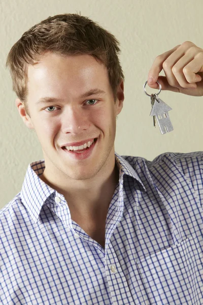 Studio shot van jonge man die sleutels aan eerste huis — Stockfoto