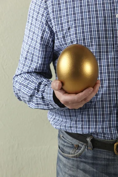 Przycięte strzał studio człowieka posiadającego złote jajko — Zdjęcie stockowe