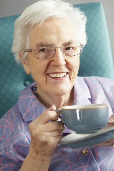 Старшая женщина расслабляется в кресле с горячим напитком — стоковое фото