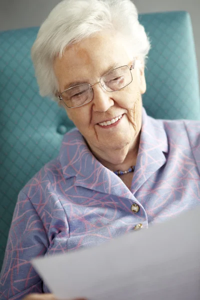 Senior mulher relaxante na cadeira leitura carta — Fotografia de Stock