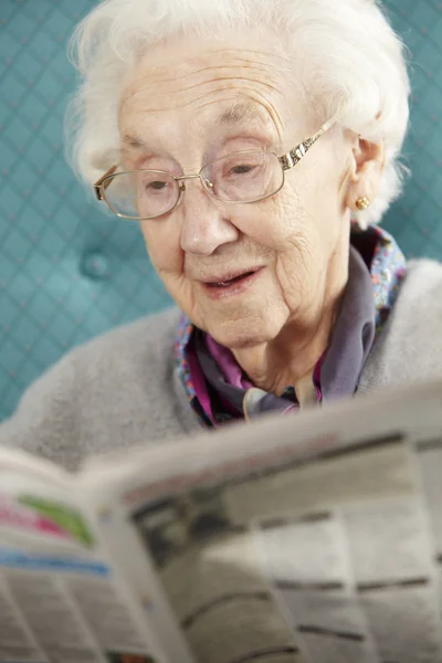 Äldre kvinna avkopplande i stol läsa tidningen — Stockfoto