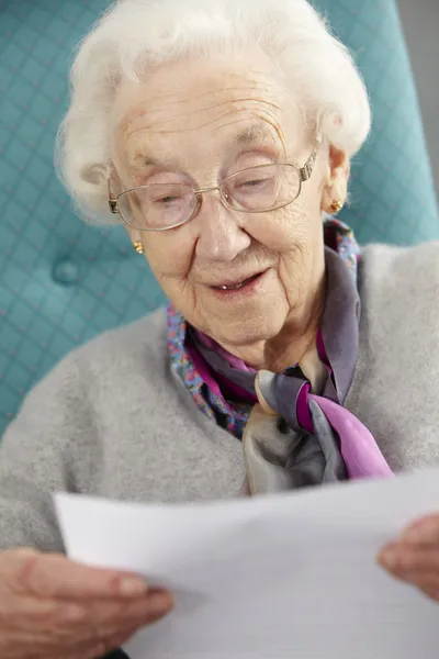 Senior vrouw ontspannen in stoel lezing brief — Stockfoto