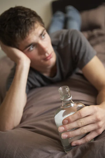 Teenage ragazzo sdraiato in camera da letto bere — Foto Stock