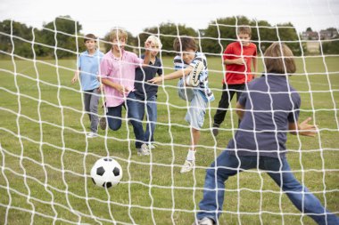 Boys playing soccer in park clipart