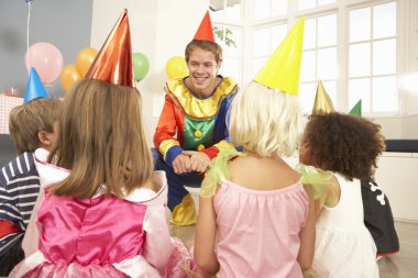 Clown entertaining children at party clipart