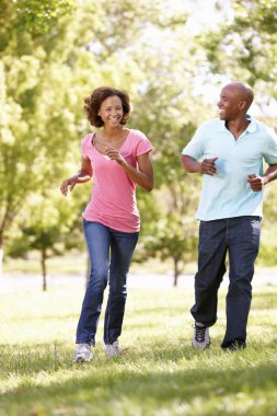 Young couple running in park clipart