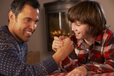 Father And Son Arm Wrestling By Cosy Log Fire clipart