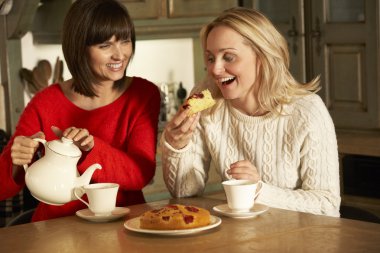 Two Middle Aged Women Enjoying Tea And Cake Together clipart