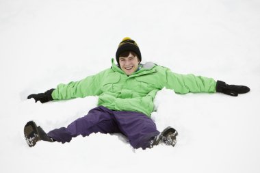 Teenage Boy Making Snow Angel On Slope clipart