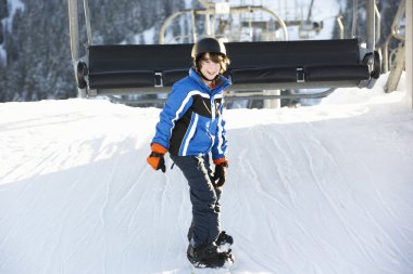 Young Boy Getting Off chair Lift On Ski Holiday In Mountains clipart