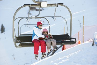 Mother And Daughter Getting Off chair Lift On Ski Holiday In Mou clipart