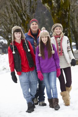 Teenage Family Walking Along Snowy Street In Ski Resort clipart