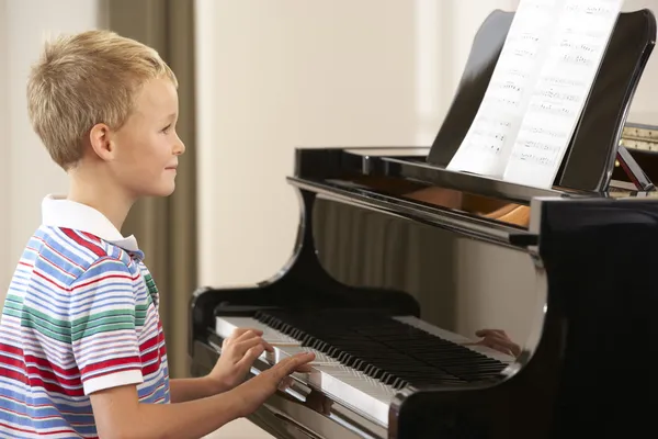 年轻男孩玩耍在家里的钢琴 — 图库照片