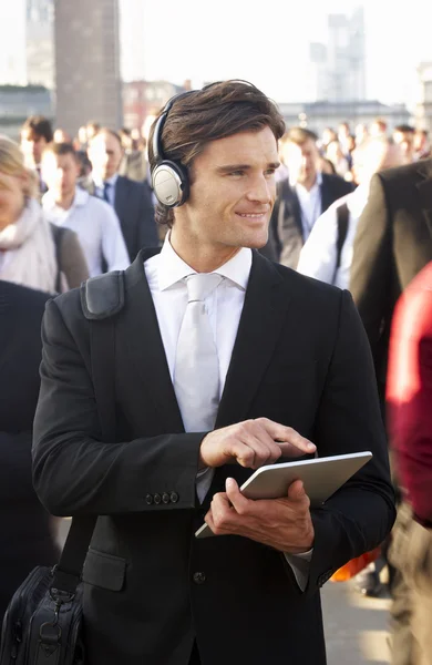 Male commuter in crowd with tablet and headphones — Stock Photo, Image