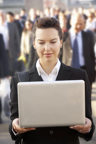 Female commuter in crowd using laptop — Stock Photo, Image