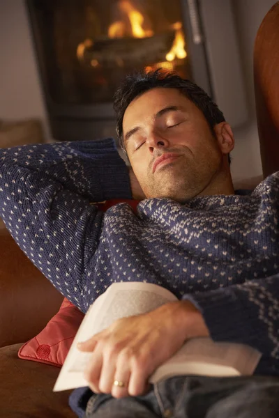 Middle Aged Man Asleep With Book By Cosy Log Fire — Stock Photo, Image