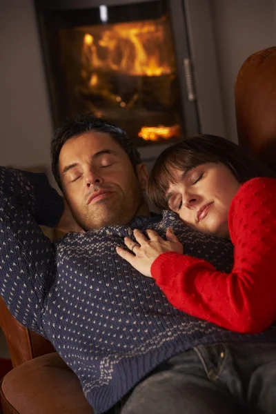 Среднего возраста пара обниматься на диване, уютный огонь журнала — стоковое фото