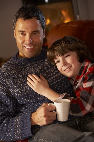 Padre e figlio rilassarsi con bevanda calda guardando la TV da accogliente log F — Foto Stock
